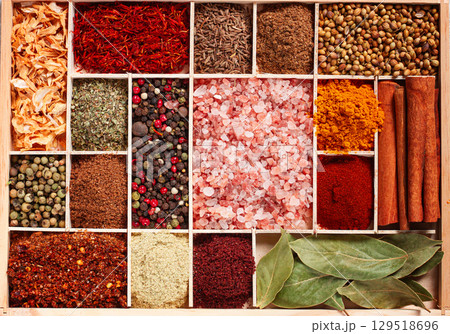 an assortment of spices laid out on a wooden tray, arranged in wooden compartments, top view, 129518696