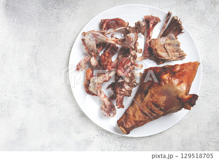 Roast pork head, with remnants of bones and meat, on a white platter, no people, close-up, 129518705