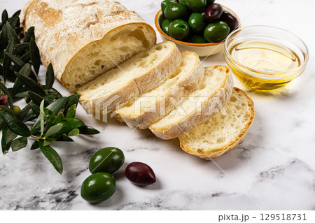 appetizer, sliced ciabatta bread, with olive oil, green olives, Chalkidiki olives, classic Green green olive, on a marble table, top view, no people, appetizer, sliced ciabatta bread, with olive oil, green olives, Chalkidiki olives, classic Green green olive, on a marble table, top view, no people, 129518731