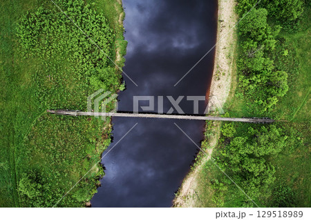 Top view of river and wooden suspension bridge in green meadow Top view of river and wooden suspension bridge in green meadow 129518989