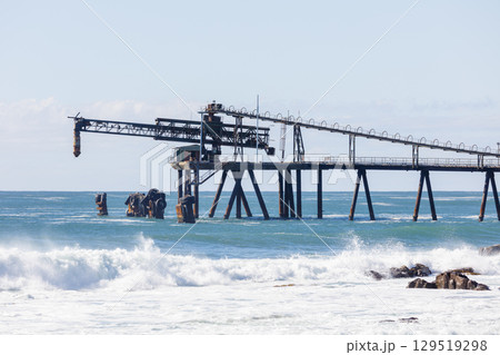 An old and weathered industrial loading jetty and crashing waves An old and weathered industrial loading jetty and crashing waves 129519298