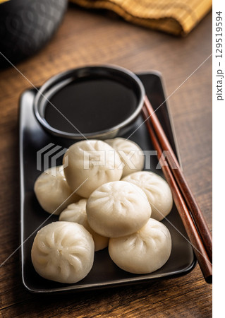 Xiao long bao. Chinese dumplings and soy sauce on wooden table. 129519594