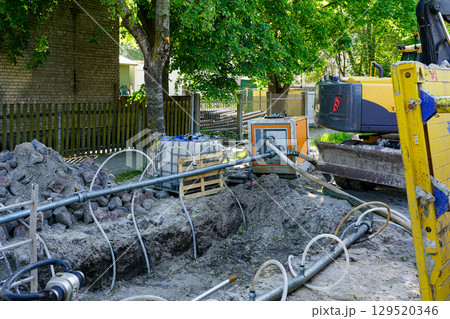 Street construction site with trenching equipment, dewatering pump, and excavator in operation 129520346