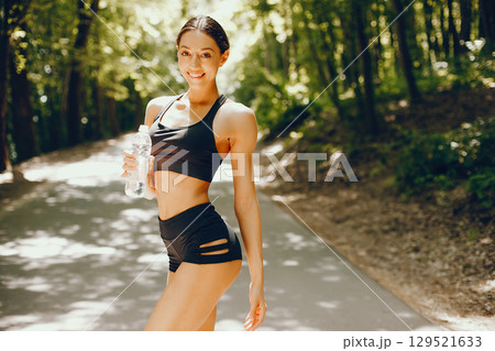 Pretty lady training in a summer park. Brunette with beauty figyre. Girl in a black top 129521633