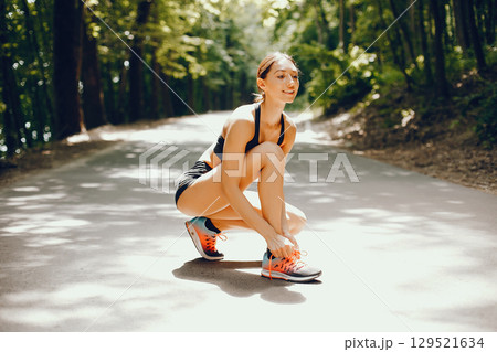 Pretty lady training in a summer park. Brunette with beauty figyre. Girl in a black top 129521634