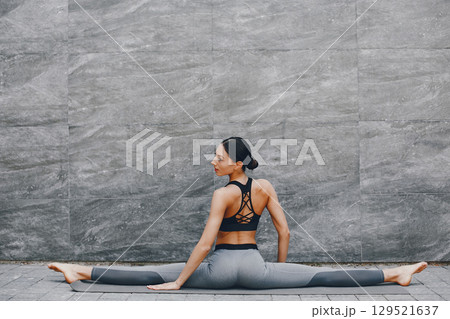 Pretty lady training in a summer city. Brunette doing yoga. Gitl in a sportsuit 129521637