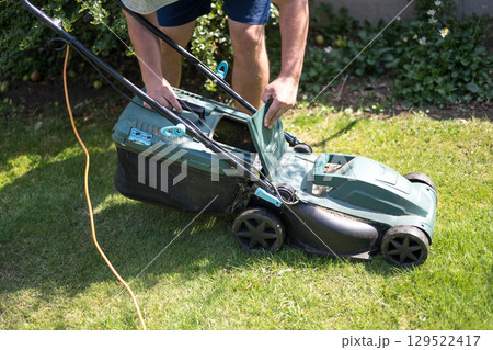 Lawn mowing in the garden, cutting green grass in the summer Lawn mowing in the garden, cutting green grass in the summer 129522417