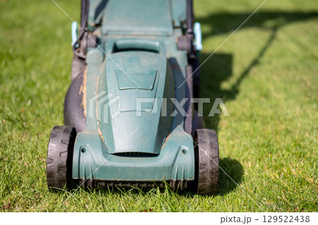 Lawn mowing in the garden, cutting green grass in the summer Lawn mowing in the garden, cutting green grass in the summer 129522438