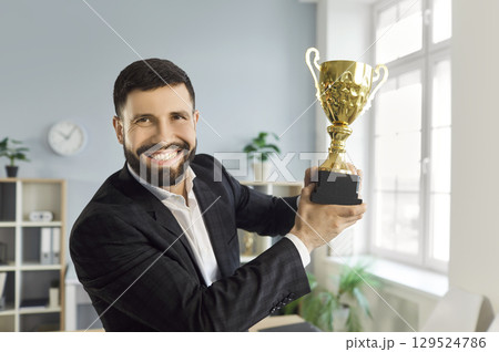 Portrait of happy man employee holding the trophy award for success in business in office. 129524786