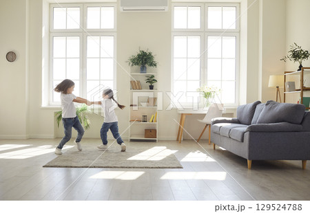 Happy brother and sister playing and having fun in big light living room at home 129524788
