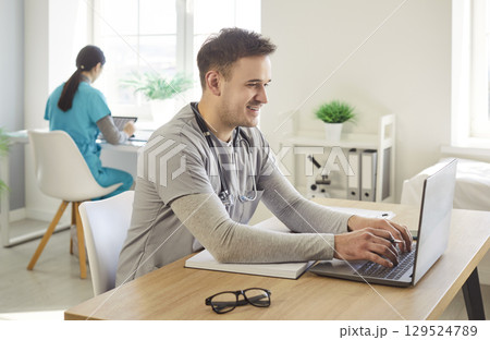 Happy Male Doctor Researching Online In Clinic Happy Male Doctor Researching Online In Clinic 129524789