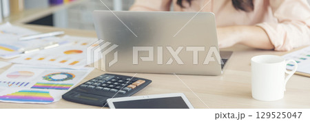 Asian Female freelance using laptop at home office desk. Woman reading financial graph chart Planning analyzing marketing data. Asian female people working office firm with business stuff, coffee cup Asian Female freelance using laptop at home office desk. Woman reading financial graph chart Planning analyzing marketing data. Asian female people working office firm with business stuff, coffee cup 129525047