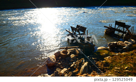 Wood water wheel Baler Machine in Agriculture Farm impeller lifted pumping water in river. Wooden Water Baler Machine green garden Farm blades by windy natural. Sustainable Resources Environment 129525049