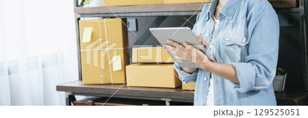 Banner Online seller Close up hands Young asian woman typing laptop keyboard checking online order on stock delivery package. Asian woman startup small business at home office with copy space 129525051