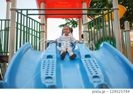 happy toddler baby girl sliding and playing at playground happy toddler baby girl sliding and playing at playground 129525784