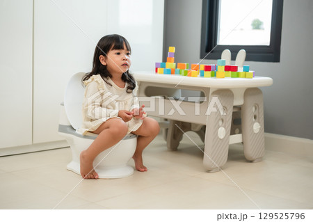 toddler girl learning sit on toilet wc seat at home. child being potty trained 129525796