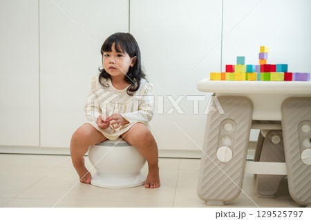 toddler girl learning sit on toilet wc seat at home. child being potty trained 129525797