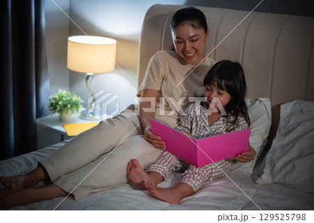 mother read story in the book for toddler girl on bed at night mother read story in the book for toddler girl on bed at night 129525798