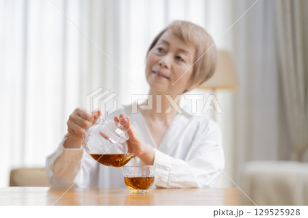 ダイニングでお茶を入れるシニア女性 ダイニングでお茶を入れるシニア女性 129525928