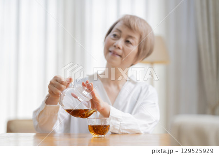 ダイニングでお茶を入れるシニア女性 ダイニングでお茶を入れるシニア女性 129525929