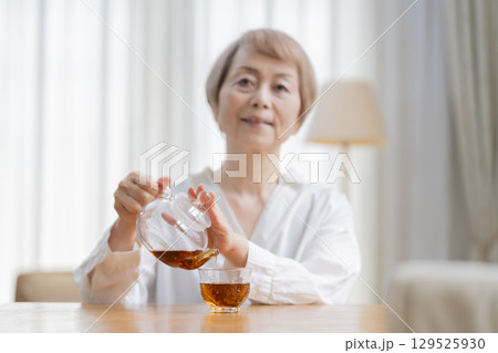 ダイニングでお茶を入れるシニア女性 ダイニングでお茶を入れるシニア女性 129525930