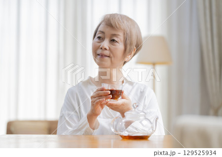 ダイニングでお茶を入れるシニア女性 129525934