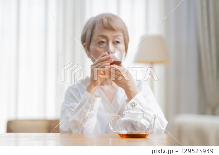 ダイニングでお茶を入れるシニア女性 129525939