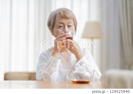 ダイニングでお茶を入れるシニア女性 129525940