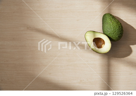 Fresh green sliced avocado on a sunlit wood tone background. 129526364