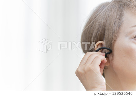 補聴器を耳に装着するシニア女性 129526546