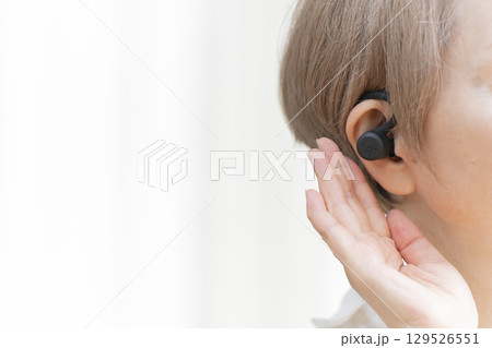 補聴器を耳に装着するシニア女性 129526551