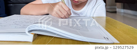 A student engages in independent learning, carefully completing workbook tasks without any assistance. A student engages in independent learning, carefully completing workbook tasks without any assistance. 129527529