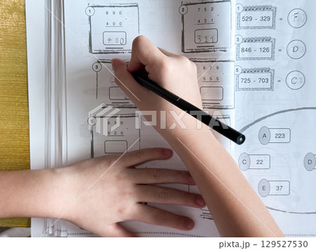 A student engages in independent learning, carefully completing workbook tasks without any assistance. 129527530