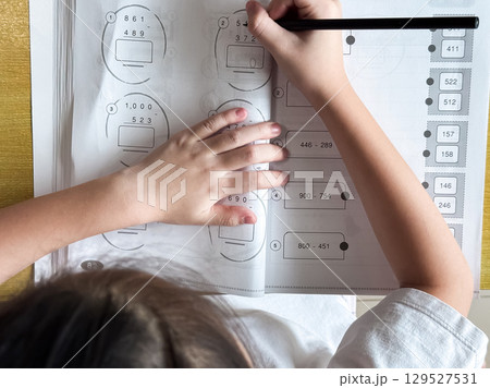 A student engages in independent learning, carefully completing workbook tasks without any assistance. A student engages in independent learning, carefully completing workbook tasks without any assistance. 129527531