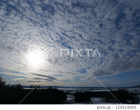 冬の午後、猪苗代湖上空に広がる白いまだら模様の雲と白く輝く太陽が青空に印象的で綺麗だ。 129528005
