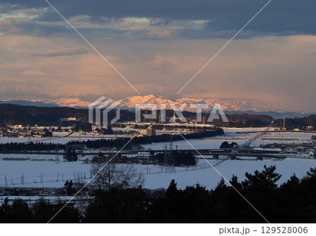 冬の早朝、朝焼けで赤く染まった雪山と白い雪原に伸びる磐越西線の線路が印象的で綺麗だ。 129528006