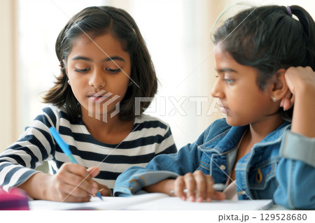 Two Girls Engaged in Study Session Focusing on Homework at Home During Daylight Hours 129528680