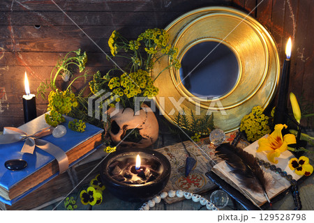 Mystic still life with magic books, tansy flowers, black candles and witchy ritual objects on old table. Occult, esoteric, gothic and wicca concept 129528798