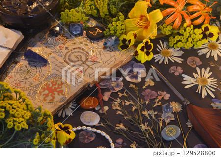 Mystic still life with open magic book of spells, flowers, crystals, black candles and witchy ritual objects on old table. Occult, esoteric, gothic  and wicca concept 129528800