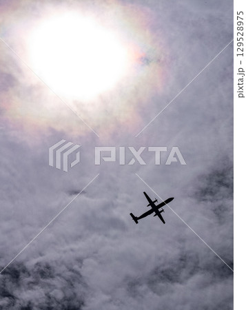 太陽を背に飛ぶプロペラ機シルエット 129528975