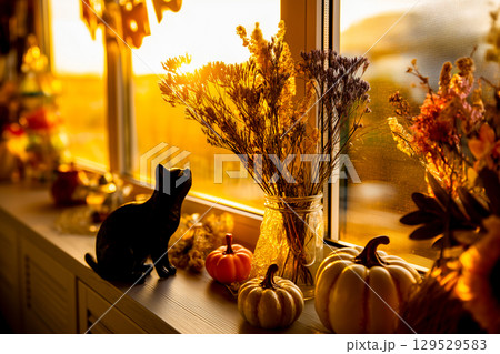 窓辺に飾られたハロウィン雑貨と猫のオブジェのシルエット（AI生成画像） 129529583
