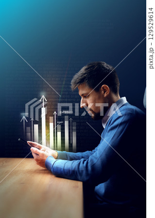 Professional man analyzing financial data on smartphone in a dimly lit office environment 129529614