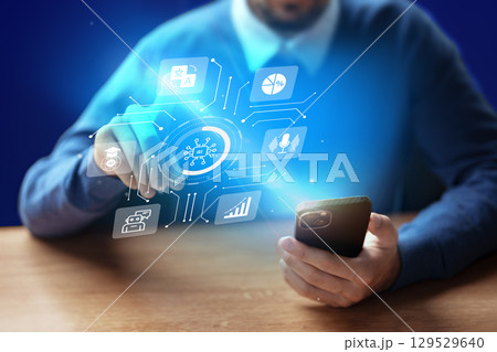 Man using smartphone with holographic technology display in modern workspace at night Man using smartphone with holographic technology display in modern workspace at night 129529640
