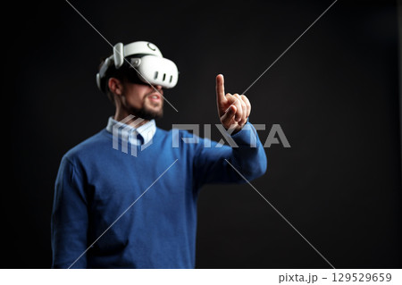 User engages with virtual reality technology while wearing a VR headset indoors 129529659