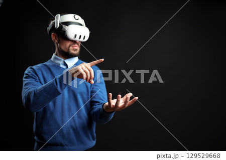 Virtual reality exploration in a dark space with a man wearing a headset and engaging with a virtual environment in real time Virtual reality exploration in a dark space with a man wearing a headset and engaging with a virtual environment in real time 129529668