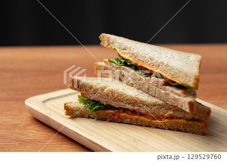 Deliciously stacked sandwich made with whole grain bread and fresh ingredients served on a wooden platter 129529760