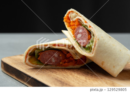 Delicious wraps filled with sausage, vegetables, and spices served on a wooden board 129529805