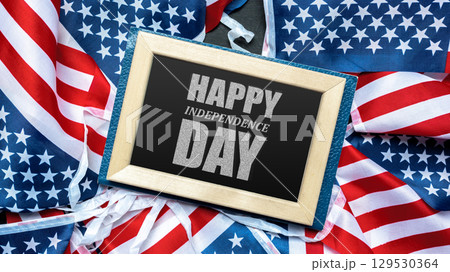 Festive celebration of Independence Day with American flags and a cheerful greeting displayed on a stylish frame Festive celebration of Independence Day with American flags and a cheerful greeting displayed on a stylish frame 129530364