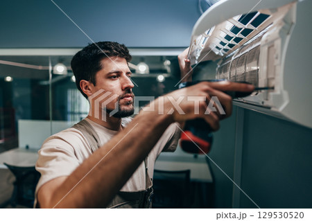 Skilled technician installs air conditioning unit in modern office space during the afternoon Skilled technician installs air conditioning unit in modern office space during the afternoon 129530520