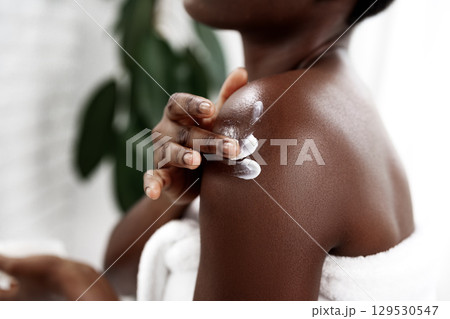 Self-care routine with moisturizer applied to shoulder in a serene indoor environment during daytime 129530547